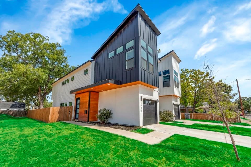 A featured Airbnb property with modern black-and-white architecture, wood accents, and a landscaped lawn.